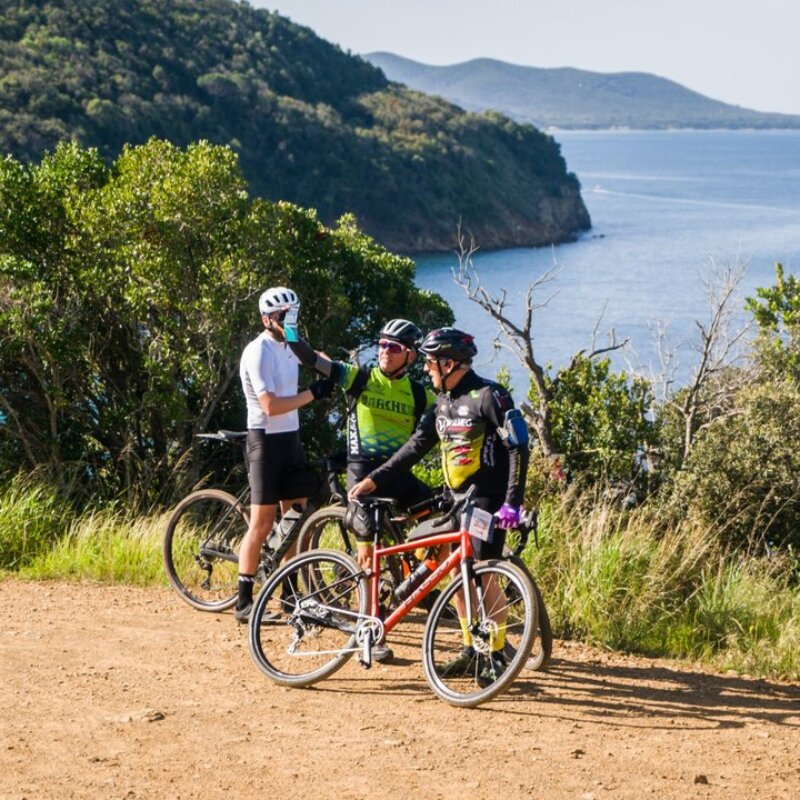 Tre ciclisti che si fermano per ammirare il paesaggio marino